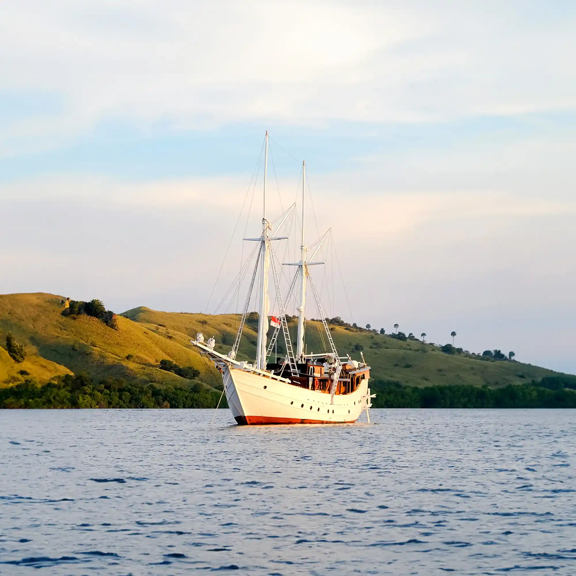 Phinisi lying at rest in flat water between charters